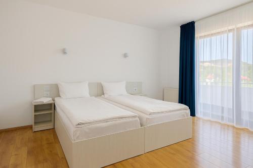 a white bedroom with a large bed and a window at PlaiulGreenbike in Deva