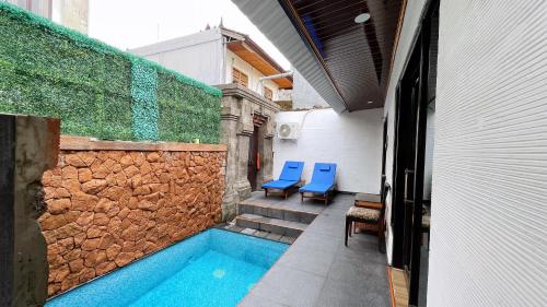 a swimming pool with blue chairs next to a building at The Tandibayang Hotel & Villas in Badung