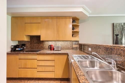 a kitchen with wooden cabinets and a stainless steel sink at Mirage Resort Villa 112 with access to Sheraton Facilities in Port Douglas