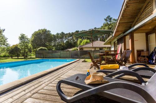 une terrasse avec des chaises et une piscine dans l'établissement Madame Vacances Villas la Clairière aux Chevreuils, à Moliets-et-Maa