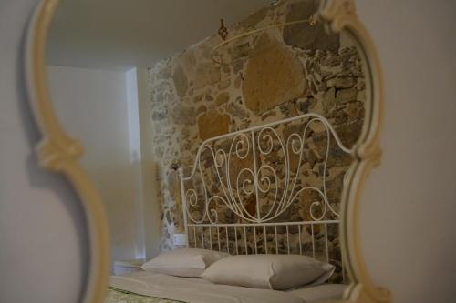 a mirror reflecting a bed in a room with a stone wall at Kritikies Lasea in Pitsidia