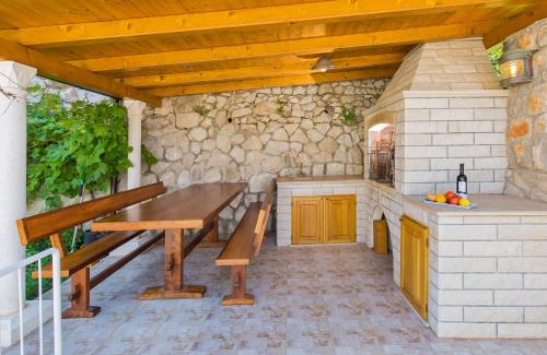 uma cozinha exterior com uma mesa de madeira e um banco em Apartments Marija Lapad em Dubrovnik