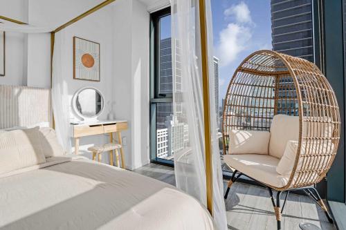 ein Schlafzimmer mit einem Bett und einem Rattanstuhl in der Unterkunft Bayside LuxePad King and Queen 2Bed 2Bath with Water Views, Gym, Lounge, Hottub in Miami