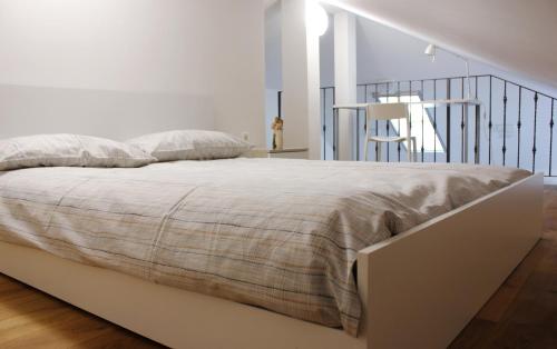 een bed in een witte slaapkamer met een trap bij Loft and Palma Apartments in Koper