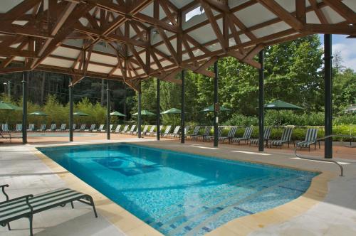 a swimming pool with chairs and a wooden roof at Grand Hotel Des Bains & Villas des Bains in Vals-les-Bains
