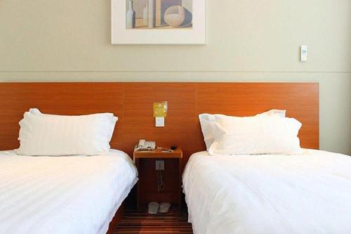 two beds sitting next to each other in a hotel room at Jinjiang Inn Style Shenyang The Palace Huaiyuan Gate in Shenyang
