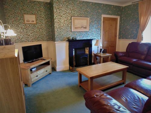 a living room with a couch and a television at Oswin Cottge in Alnwick