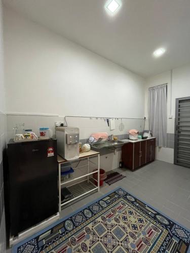 a kitchen with a black refrigerator and a rug at Muqryy Homestay in Marang