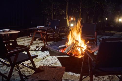 a fire pit with chairs and chairs around it at night at 高尾山すぐ貸切villa都心から70分自然豊か貸切サウナ道志ツーリングBBQ焚火花火日本庭園 in Sagamihara