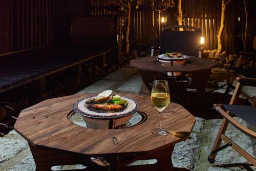 a table with a plate of food and a glass of wine at 高尾山すぐ貸切villa都心から70分自然豊か貸切サウナ道志ツーリングBBQ焚火花火日本庭園 in Sagamihara