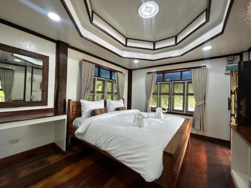 Un dormitorio con una cama grande en una habitación con ventanas. en Baan Home Resort, en Kalasin