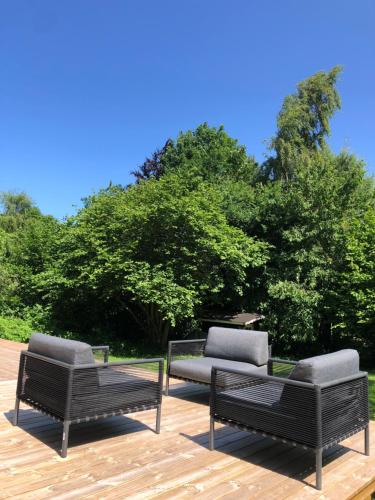 two benches and a couch on a wooden deck at Liseleje sommerhus på naturgrund in Melby