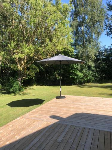 an umbrella sitting on top of a wooden deck at Liseleje sommerhus på naturgrund in Melby