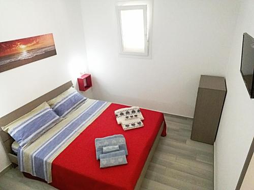 トッレ・ラピッロにあるCasa Vacanza Carmineのベッドルーム1室(赤いベッド1台、赤いテーブル付)