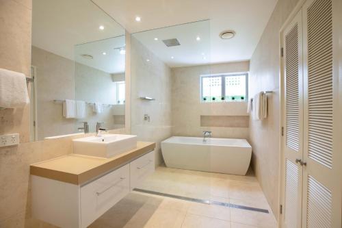a bathroom with two sinks and a tub and a mirror at Mirage Resort Villa 428 with access to Sheraton Facilities in Port Douglas