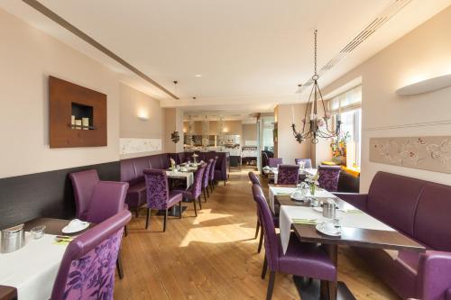 une salle à manger avec des chaises et des tables violets dans l'établissement Novum Hotel Post Aschaffenburg, à Aschaffenbourg