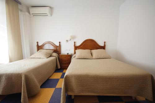 1 dormitorio con 2 camas y suelo amarillo y azul en Hostal Restaurante la Trucha, en Benavente
