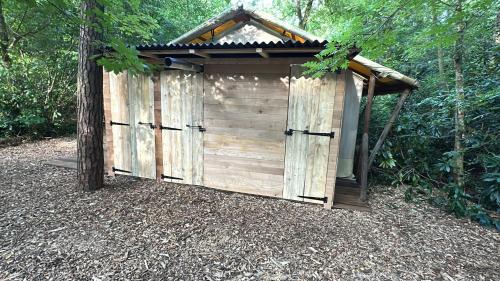 a wooden outhouse in the middle of a forest at Glampingtent Bosgenot in Zedelgem