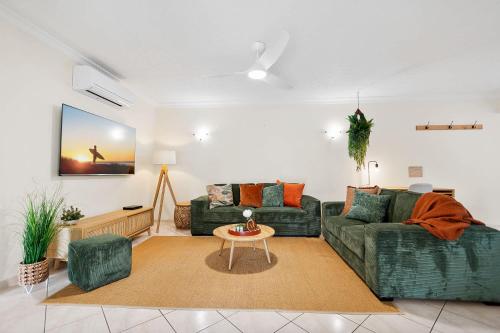 ein Wohnzimmer mit einer grünen Couch und einem Tisch in der Unterkunft Lakeside Luxe Retreat - Pool View BBQ Spa Bath in Cairns North