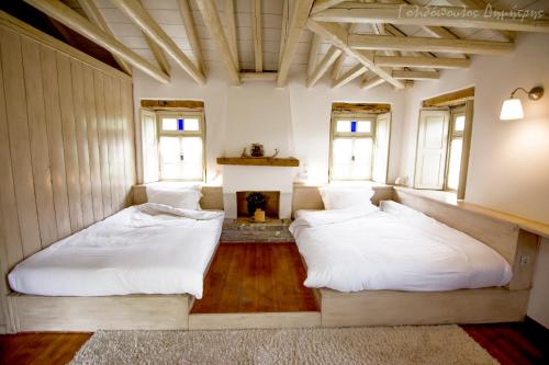 two beds in a room with a fireplace at Papaevangelou Hotel in Papigko