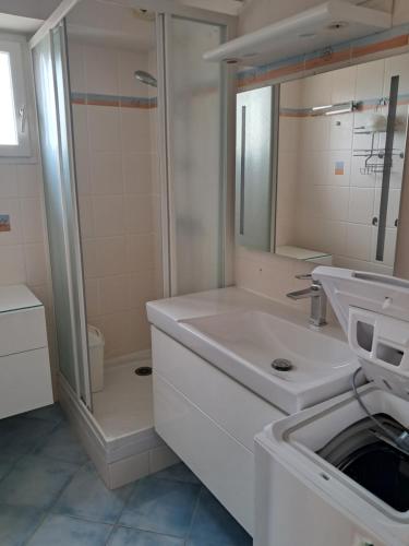 a white bathroom with a sink and a shower at appartement T2 climatisé résidence azur 219 in Le Lavandou