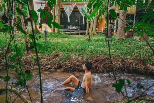 a young boy sitting in the water in a creek at ภูธารา กลางดง in Ban Thung Phan Ha