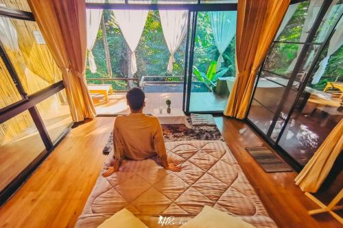 a person sitting in a room looking out of windows at ภูธารา กลางดง in Ban Thung Phan Ha