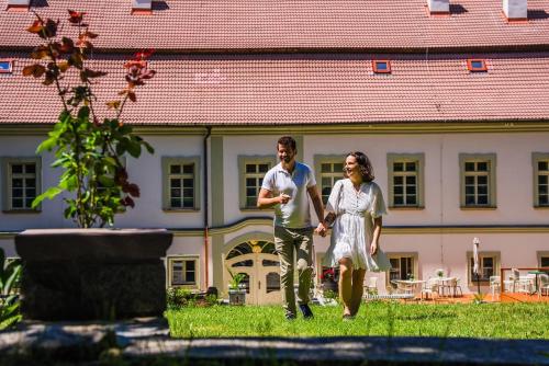 a man and a woman walking in front of a building at Zámek Načeradec in Načeradec
