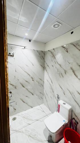 a white bathroom with a toilet and a shower at 7th Heaven Hotel in Hisār
