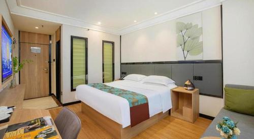 a bedroom with a large white bed and a living room at GreenTree Inn Puyang Pushang Huanghe Road in Puyang