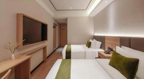 a hotel room with two beds and a flat screen tv at GreenTree Inn Puyang Pushang Huanghe Road in Puyang