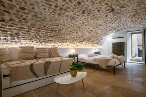 une chambre avec un lit et un mur en pierre dans l'établissement L'Écrin de Pierre dans un cadre de vie unique, à Saint-Laurent-du-Var