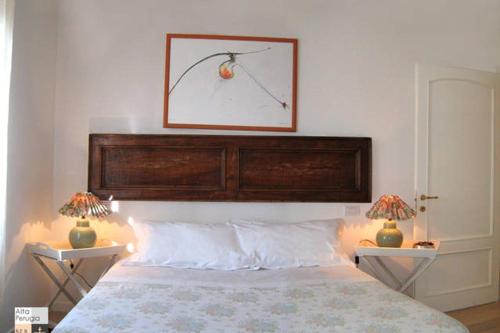 Alta Perugia B&B في بيروجيا: غرفة نوم مع اللوح الأمامي الخشبي الكبير وطاولتين جانبيتين