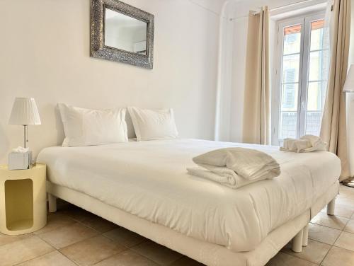 - une chambre avec un lit blanc et un miroir mural dans l'établissement Cannes 2 Bedroom Apartment - 19JDR2, à Cannes