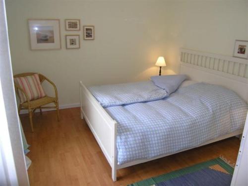 a bedroom with a bed with a lamp and a chair at Ferienhaus Friedrich-Borge-Straße in Kühlungsborn