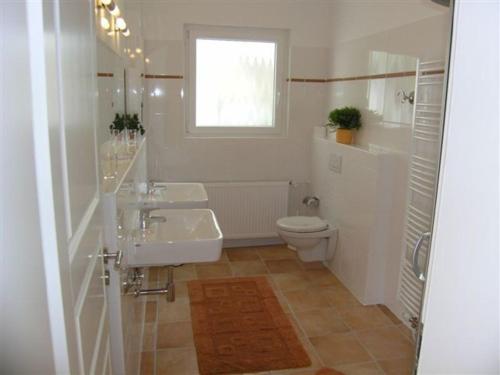 a bathroom with two sinks and a toilet and a window at Ferienhaus Friedrich-Borge-Straße in Kühlungsborn