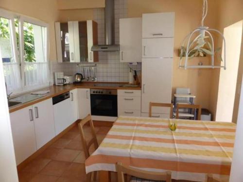 a kitchen with white cabinets and a table with chairs at Ferienhaus Friedrich-Borge-Straße in Kühlungsborn