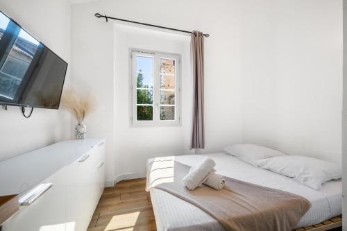une chambre blanche avec un lit et une télévision à écran plat dans l'établissement Studio Cosy Vieille Ville, à Saint-Laurent-du-Var