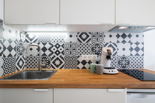 - une cuisine avec du carrelage noir et blanc sur le mur dans l'établissement Studio Cosy Vieille Ville, à Saint-Laurent-du-Var