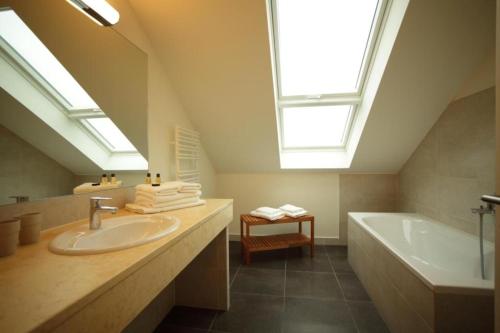 ein Badezimmer mit einem Waschbecken, einer Badewanne und einem Dachfenster in der Unterkunft Appartement Schloß - Hohen Niendorf in Hohen Niendorf