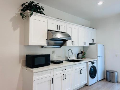 Una cocina con gabinetes blancos, un fregadero y un microondas. en #Marbella Lane - Lit & Laid Back Eastvale Home, en Corona
