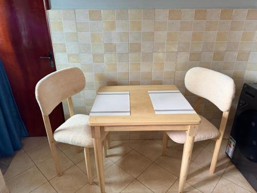 a wooden table with two chairs and a book on it at Kampala Comfort 1 in Nalakonge