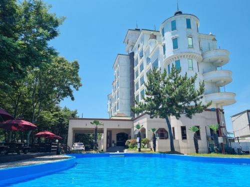 a hotel with a swimming pool in front of a building at Namhae Beach Hotel in Namhae