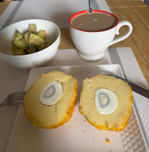 a sandwich on a plate with a cup of soup at Kampala Comfort 1 in Nalakonge