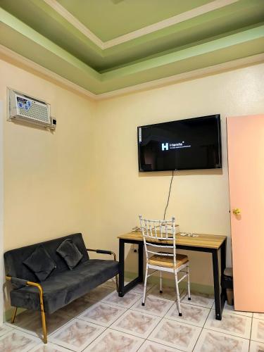 a living room with a couch and a table and a tv at Legends Apartel in Lemery