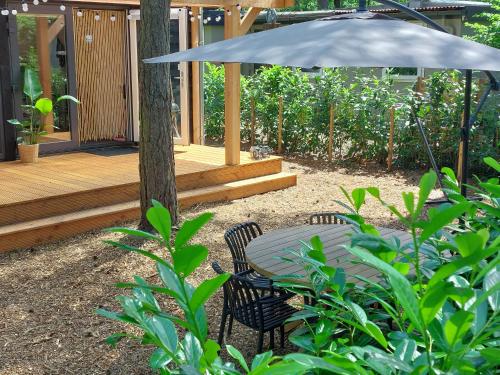 a patio with a table and chairs and an umbrella at Thuisje van Hout, tiny house in Drentse natuur in Zuidwolde