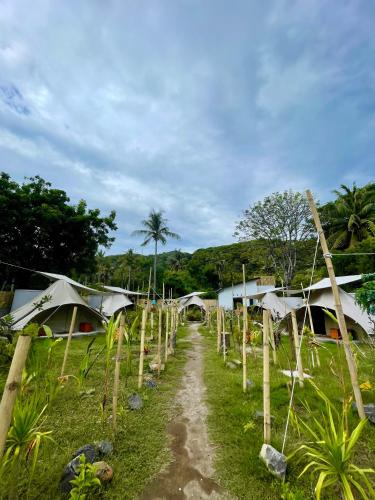 ギリ・トラワンガンにあるUbuntu Glamping - Adult Campers Onlyのテントが張られた野原を通る未舗装道路