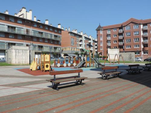 un parque infantil con bancos y equipo de juegos en una ciudad en Apartamento Jarrillero, en Portugalete