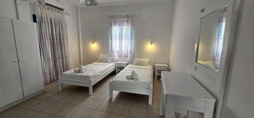 a room with two beds and a table and a mirror at Hostel Pleasure Black Beach Parissa Santorini in Perissa