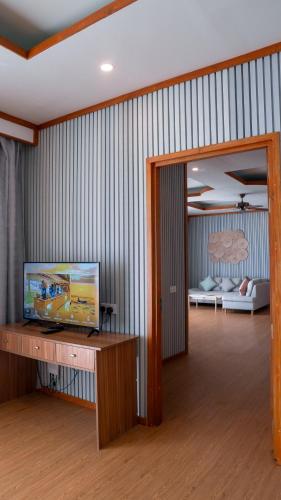 a living room with a television and a room with a bed at Brennia Kottefaru Maldives in Raa Atoll